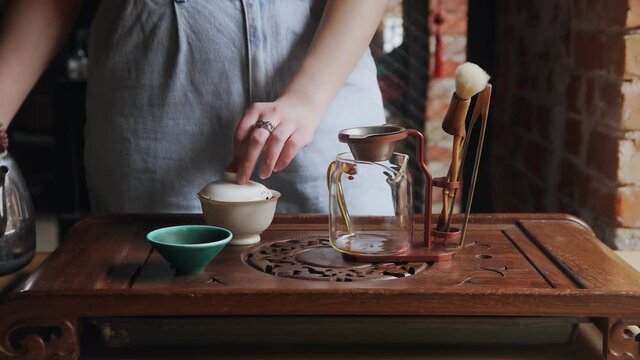 Close Up of woman Pouring Green Tea from Gaiwan to glass Teapot