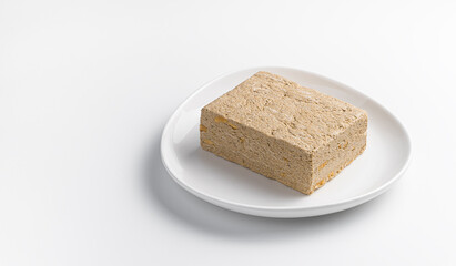 A portion of classic halva on a white plate on a light background.