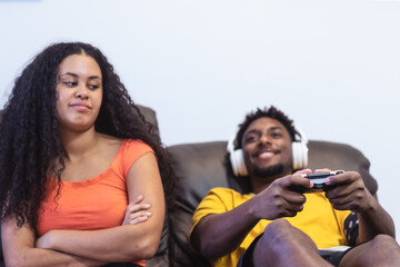 Boy is playing playstation computer game and woman girlfriend is angry for him. Technology and relationship concept. Focus on joystick
