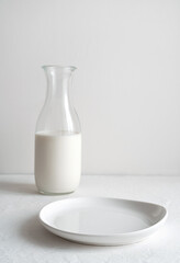 Minimalistic vintage background with an empty plate and a jug of milk in the background.