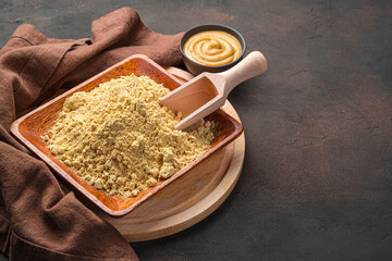 Mustard powder close-up on a dark brown background.