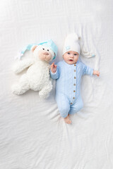 Obraz premium a baby on a bed in a hood goes to bed or wakes up in the morning. Textiles and bedding for children. Newborn baby with a toy bear