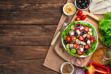 Fototapeta na wymiar Greek salad and ingredients on a brown wooden background.