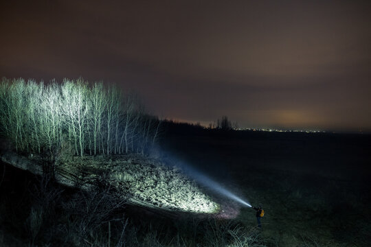 Man With Flashlight in Forest at Night