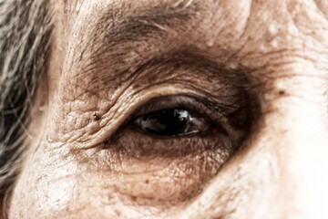 Close up of an person looking up - Elderly face over black background - Eyes of an old asian woman, old wrinkled face of an old mother