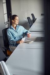 Attractive female office manager daydreaming during the coffee break