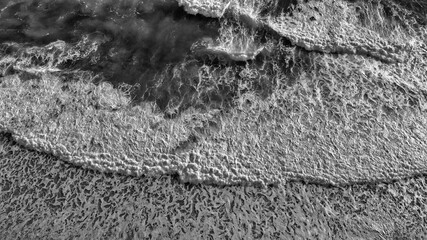 Waves along the shoreline at sunset, aerial view from drone