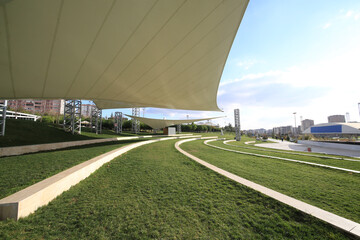front view, empty activity and parking space with grass floor. Large horizontal awnings protecting from rain and sun. open space for concert and theater