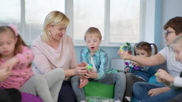 woman teacher conducts developmental activities for children with down syndrome and assembles development kit