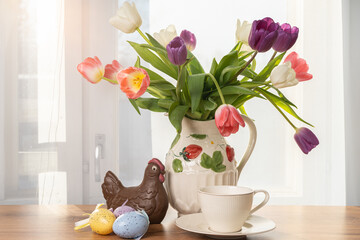 Blooming tulips, chicken from chocolate, Easter eggs, on the background of the window Concept of congratulations on Easter, Happy Easter.