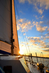 white sail yacht white against the blue sky with clouds and sun