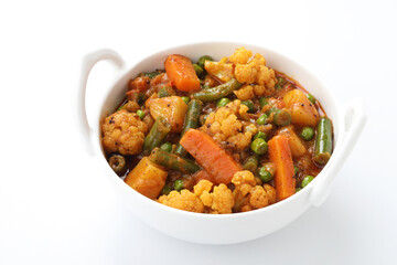 MIX VEGETABLE CURRY- indian recipe, mixed veg containing Carrots, cauliflower, green peas and beans with traditional masala and curry, red hot and spicy served in a ceramic bowl
