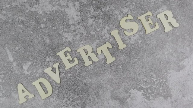 Advertiser concept with decorative alphabet letters in an undulating line on a textured grey background viewed as a flat lay with copyspace. Rotation