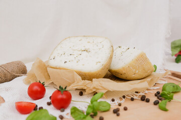 Medium hard cheese head parmesan on wooden board, with cheese parmesan with tomatoes on the table