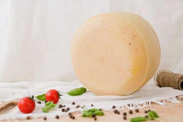 Medium hard cheese head parmesan on wooden board, with cheese parmesan with tomatoes on the table