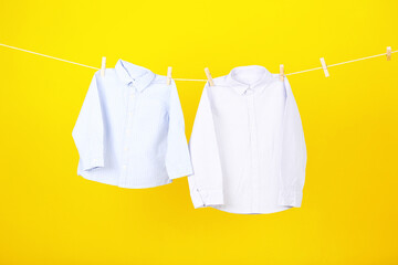 Baby clothes hanging on yellow background
