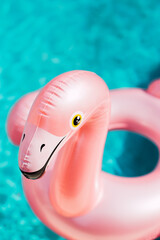 Pink flamingo inflatable swimming ring pool float on blue pool water with ripples on a sunny day. Summer time relaxation concept. Colorful and joyful background. Chill lifestyle. © Andra