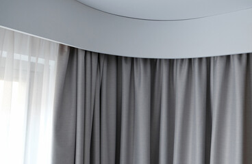 Angular cornice with drapes and white curtain or tulle. Interior details close up. White wall,...