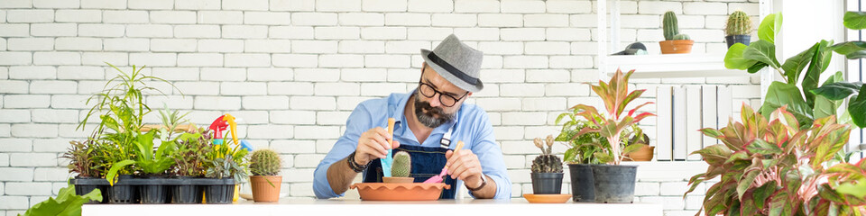 An elderly man handsome with have mustache wearing glasses is happy with tree care. is a hobby of...