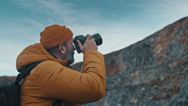 Landscape photographer while he is taking pictures of nature during autumn in the mountains.