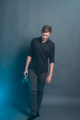 The guy walks on a gray background with blue smoke with a bottle of alcohol