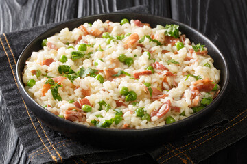 Risi e Bisi Arborio rice with green peas and prosciutto close-up on a plate on the table. horizontal