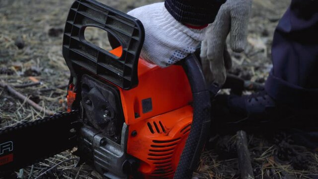 a man starts a chainsaw in the woods