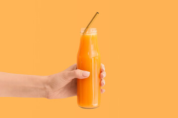 Female hand with bottle of tasty smoothie on color background