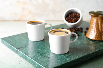 Fototapeta na wymiar Cups of tasty hot coffee on grunge background
