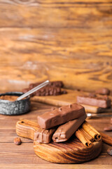Sweet chocolate bars and cinnamon on wooden background