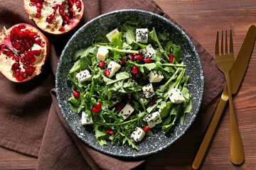 Bowl of arugula salad on wooden background