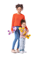 Portrait of cute African-American sisters with skateboards on white background