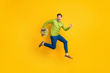 Fototapeta na wymiar Full length body size profile side view of nice cheery crazy guy jumping running carrying flowers floristry isolated on vivid yellow color background