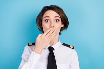 Photo of amazed shocked young woman hold hand face cover mouth wear pilot uniform isolated on blue color background © deagreez