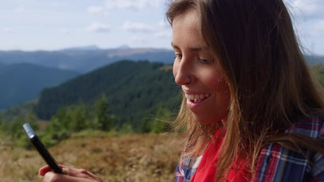 Girl using smartphone in mountains. Woman typing message on mobile phone 