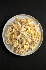 Homemade Garlic Shrimp Bacon Alfredo on a plate on a black background, top view. Flat lay, overhead, from above.