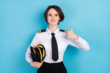 Photo of happy nice young woman show thumb-up recommend advert trip hold hat isolated on blue color background © deagreez