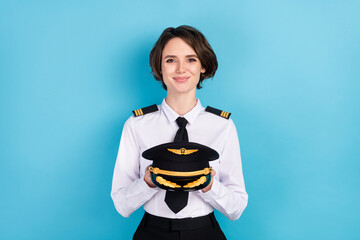 Photo of happy attractive young woman hold uniform pilot hat good mood isolated on blue color background © deagreez