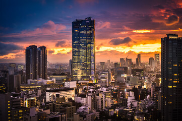 Naklejka premium Sunset of Tokyo Skyline and the Illuminated City. Lights in Windows and Dusk View of Big Endless City.