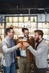 Young businessmen are drinking beer, talking and smiling while resting at the pub