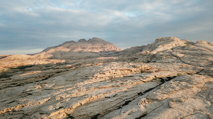 Dawn over frozen lava and mountains. Huge rocks and a gorge cast a shadow from the sun. Grass and...