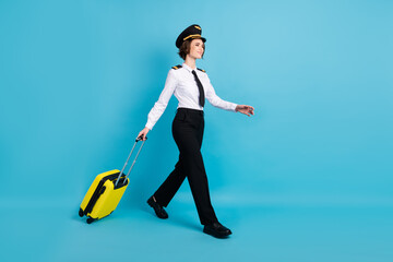 Full size profile photo of optimistic nice brunette hair lady carry bag go look empty space wear pilot uniform isolated on blue background
