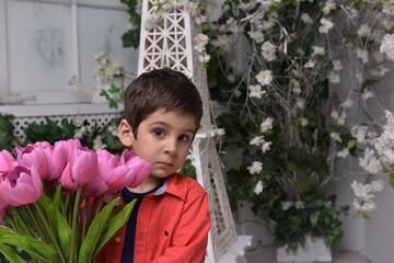 Little boy in a red shirt and a bouquet of tulips in his hands