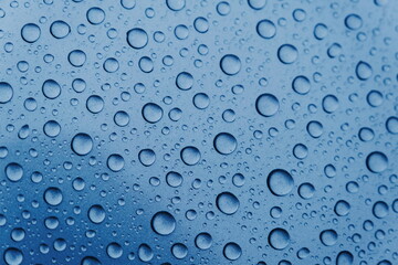 Close-up of water droplets and drops on a blue surface. Texture and structure after rain. Ecology.