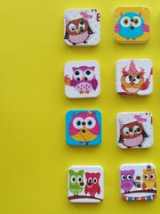 square wooden buttons with drawings of owls on a yellow background