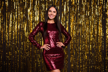 Photo of young beautiful smiling positive charming girl in red shiny dress posing at party isolated on glittered background
