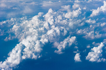 Naklejka na ściany i meble Cumuluswolken am blauen Himmel vom Flugzeugfenster aus gesehen