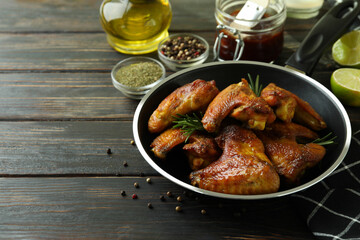 Concept of tasty food with baked chicken wings on wooden background, space for text