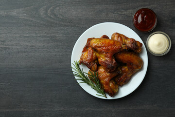 Concept of tasty food with baked chicken wings on dark background, space for text