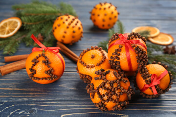 Pomander balls made of fresh tangerines and cloves on blue wooden table